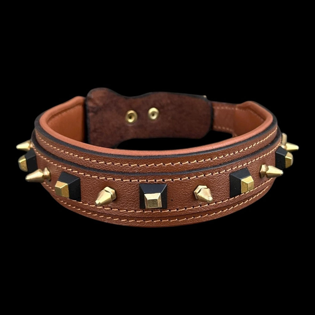 A&C Dog Collars el yapımı kahverengi manda derisi köpek tasması, altın sivri uçlar ve siyah geometrik çivilerle süslü.