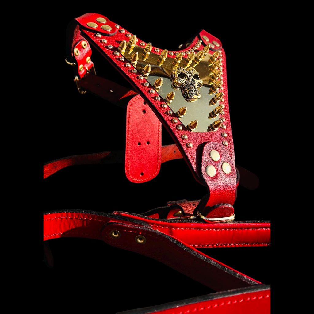 A&C Dog Collars red buffalo leather harness featuring a gold Punisher logo plate and heavy-duty brass spikes.