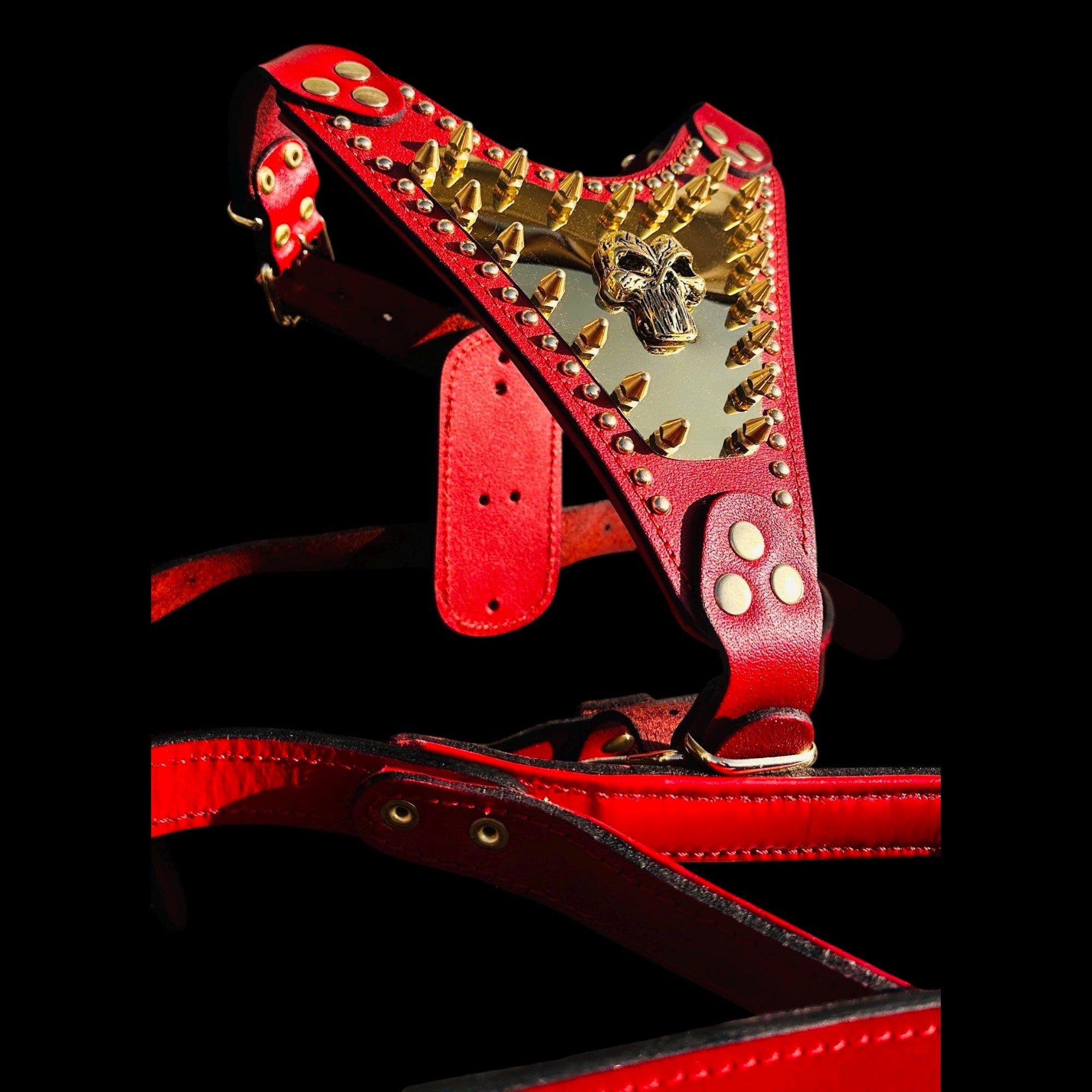 A&C Dog Collars red buffalo leather harness featuring a gold Punisher logo plate and heavy-duty brass spikes.
