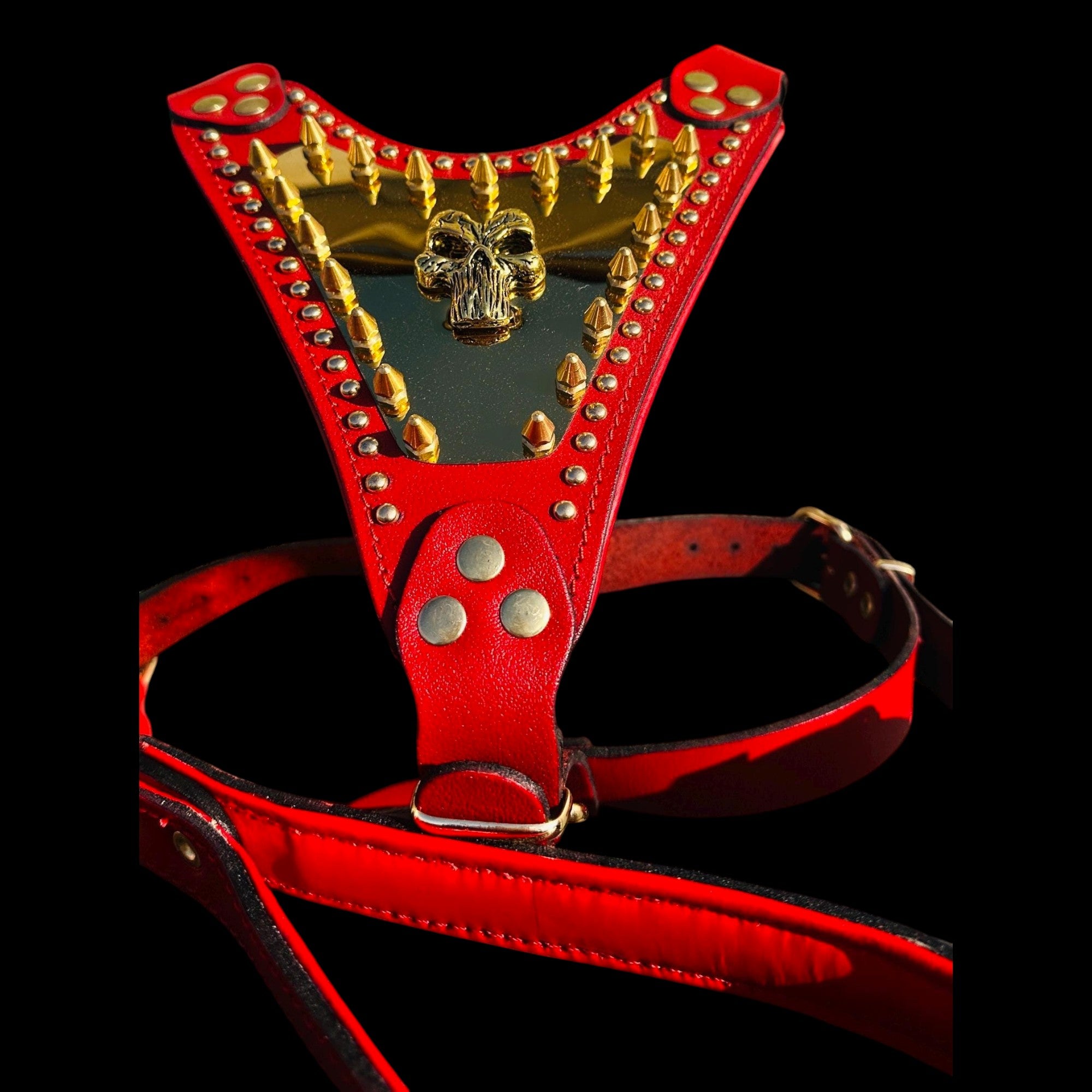 A&C Dog Collars red buffalo leather harness featuring a gold Punisher logo plate and heavy-duty brass spikes.
