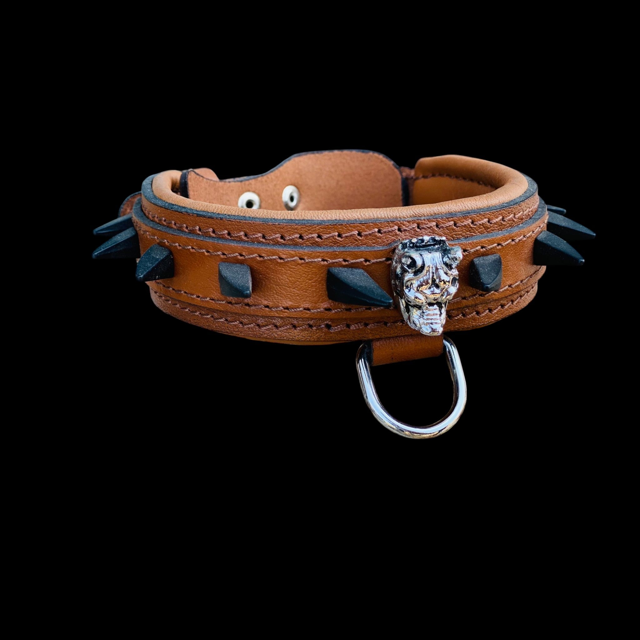 Detailed shot of handmade brown dog collar with black spikes, padded interior, and strong stitching