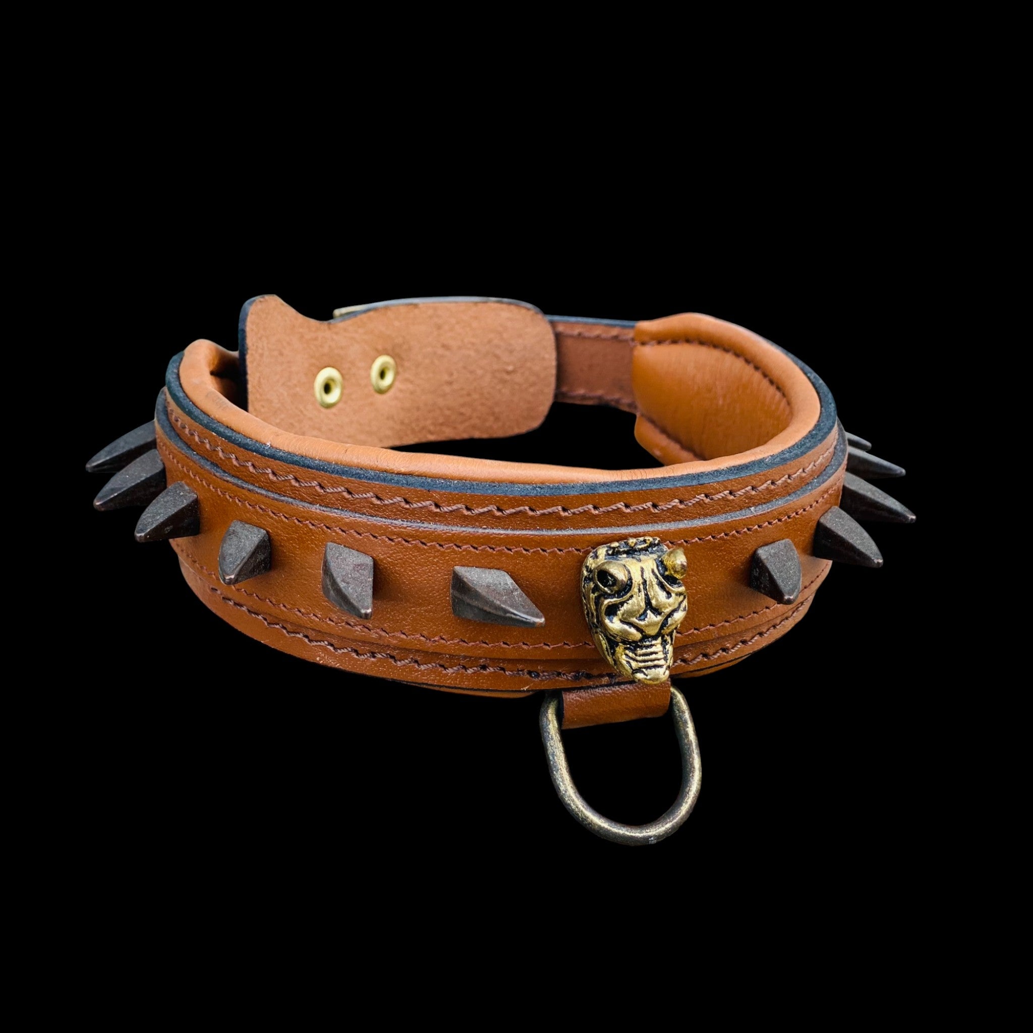 Close-up detail of brown leather dog collar showing ivory spike studs, Bully head logo and reinforced stitching for strength and style