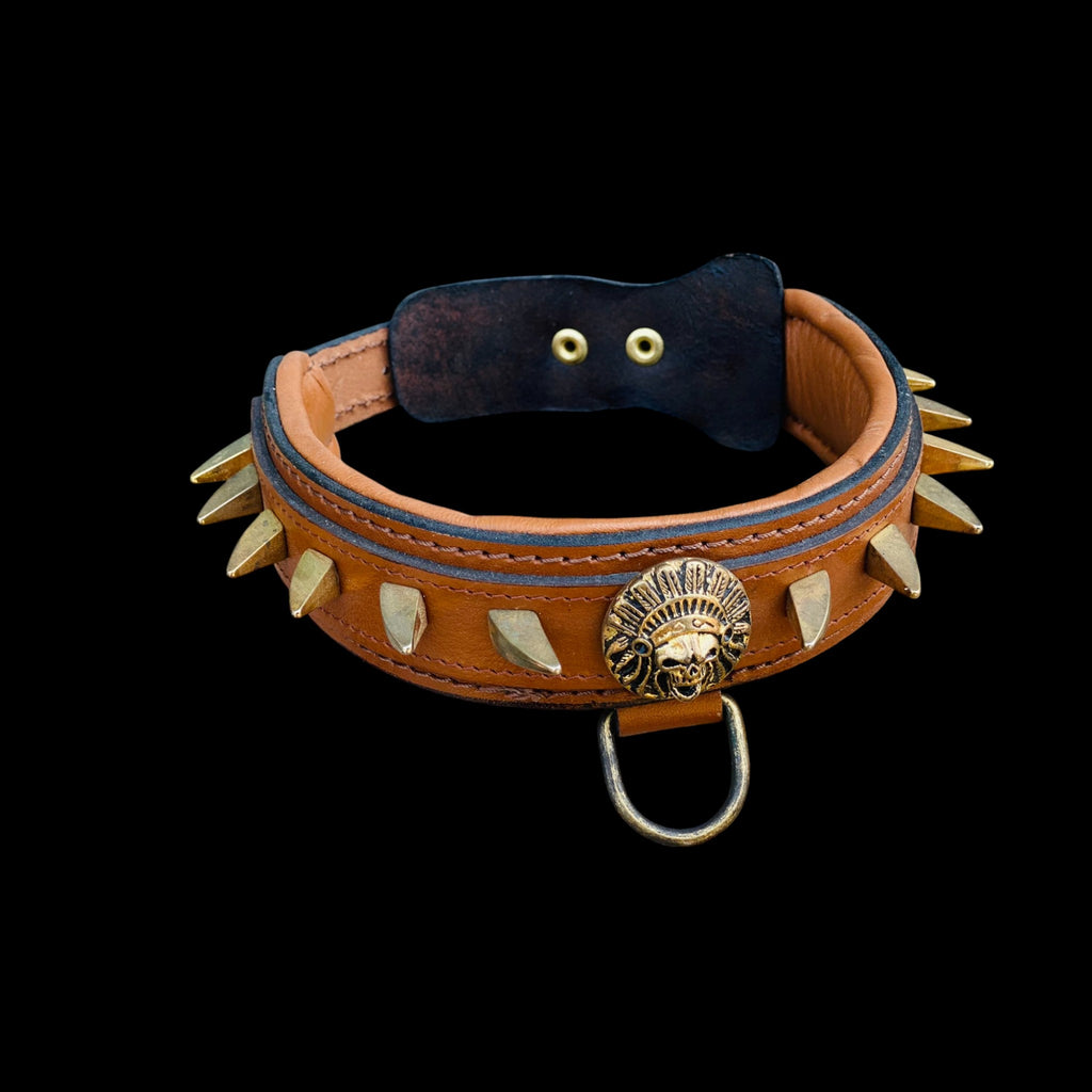 Close-up of Native American logo centerpiece and gold ivory spikes on brown leather collar.