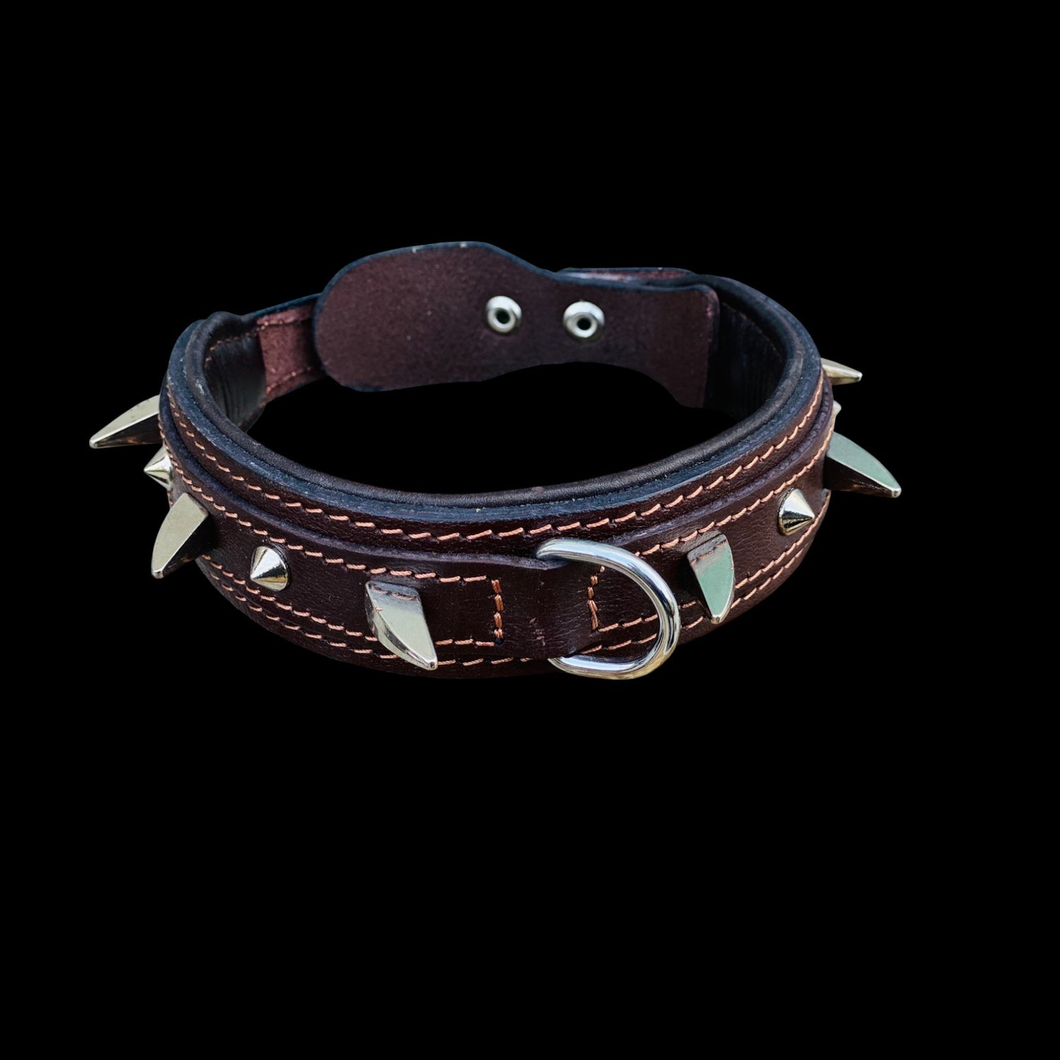 Close-up detail of brown spiked dog collar showing genuine leather, heavy duty studs, reinforced stitching and steel hardware