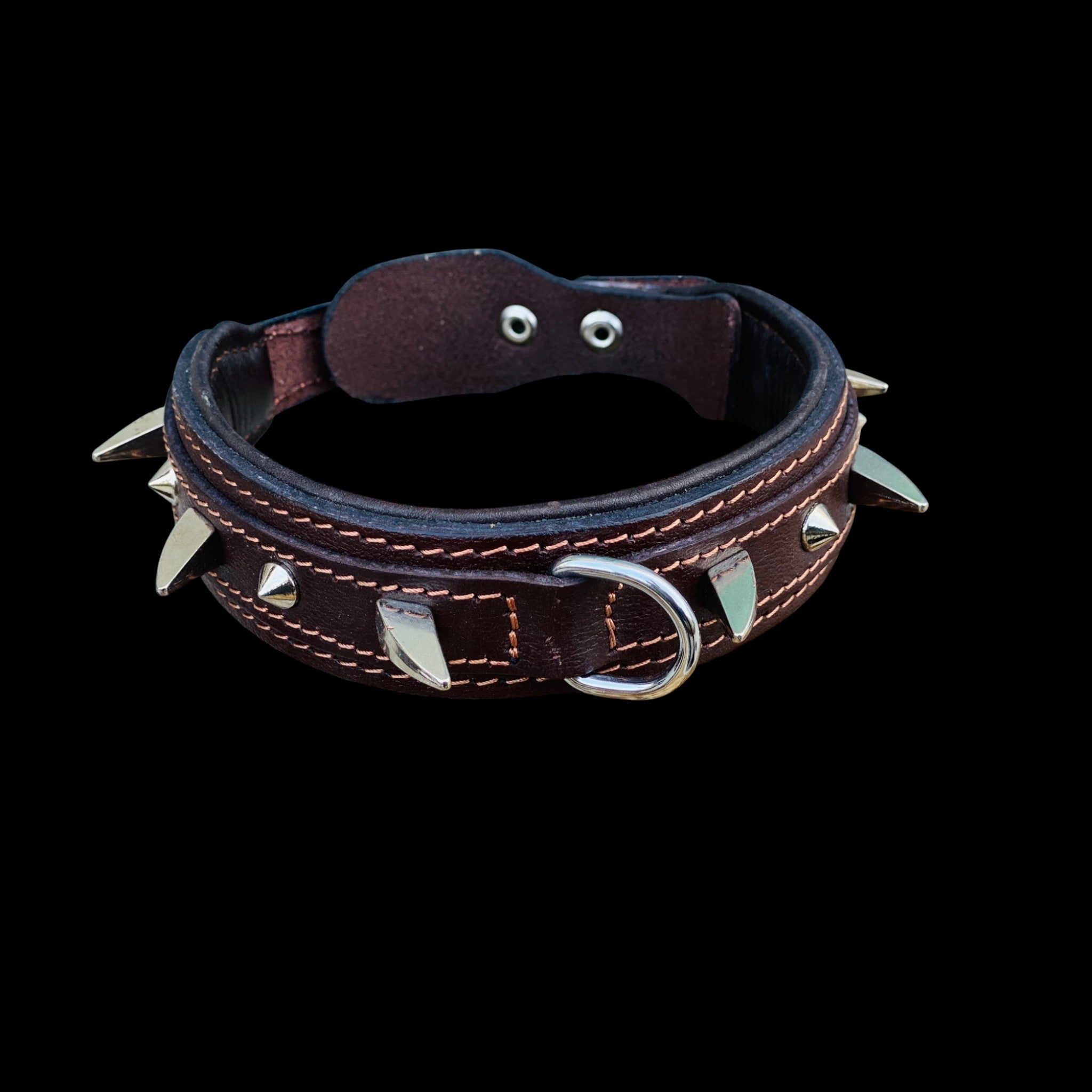 Close-up detail of brown spiked dog collar showing genuine leather, heavy duty studs, reinforced stitching and steel hardware